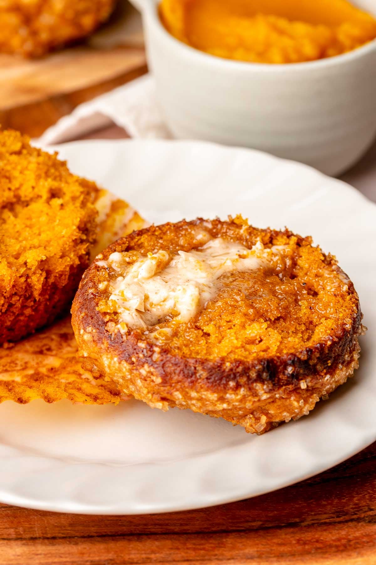 A pumpkin muffin with the top removed and butter on top.
