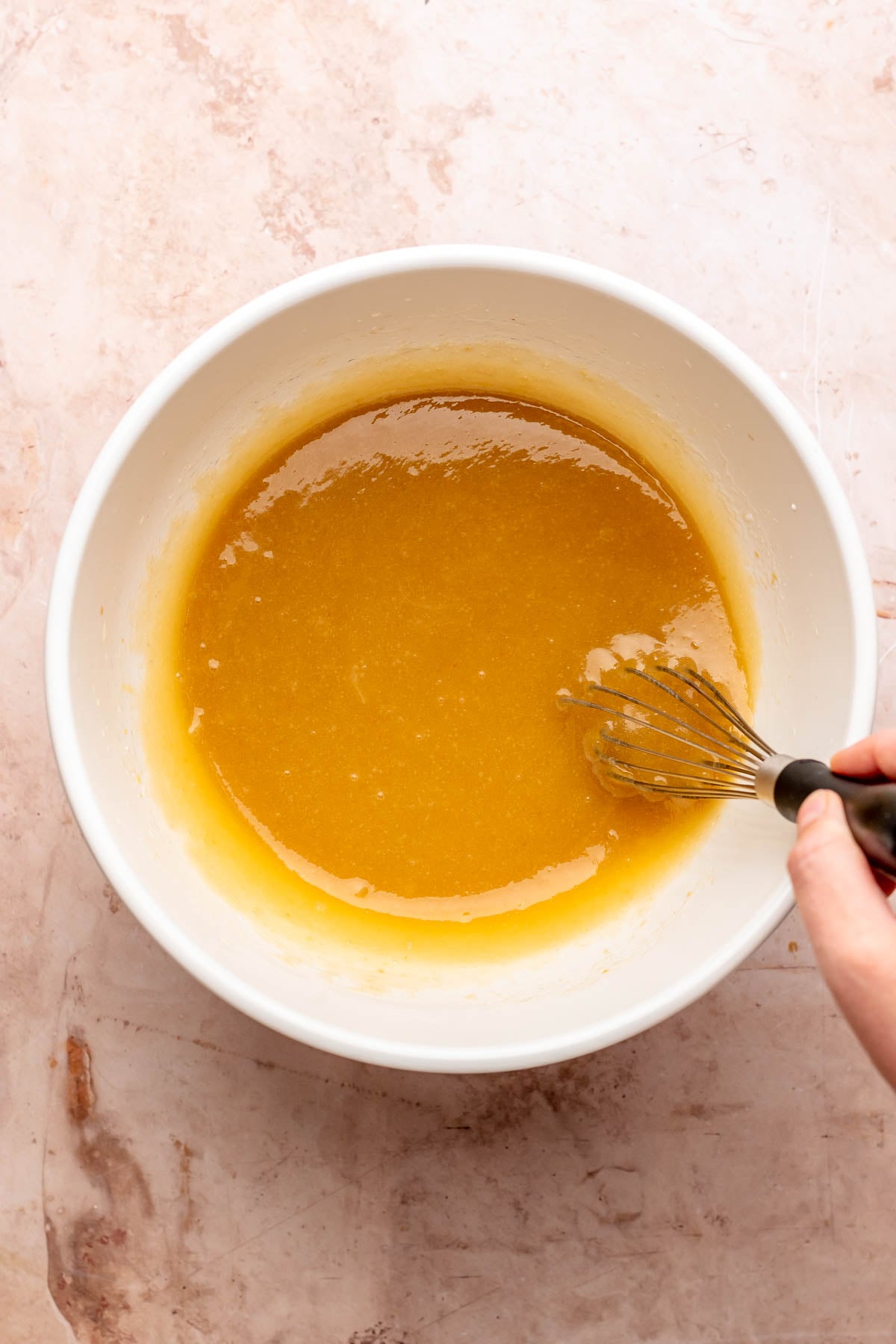 A whisk mixes wet ingredients in a bowl.