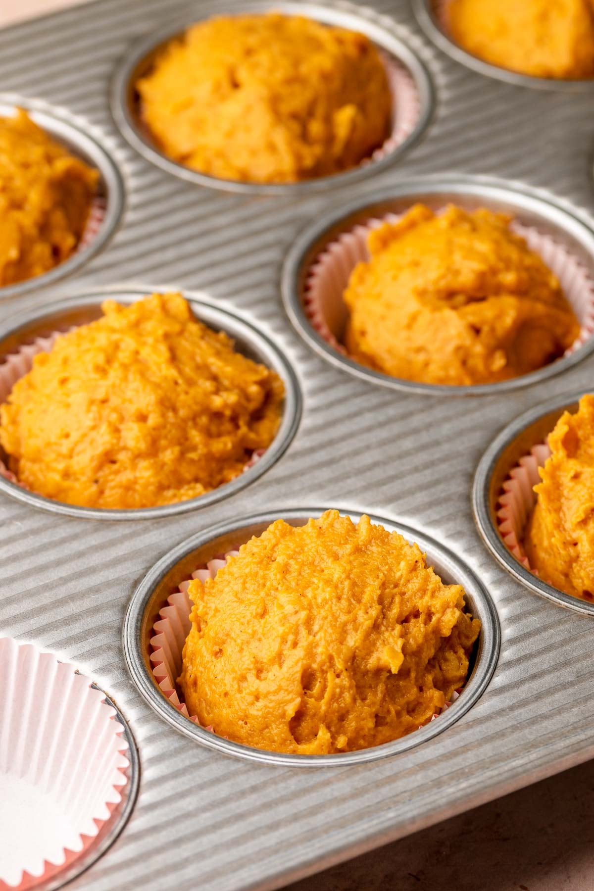 Pumpkin muffin batter in a muffin tin.