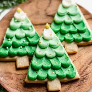 Three Christmas Shortbread Cookies on a wooden plate.