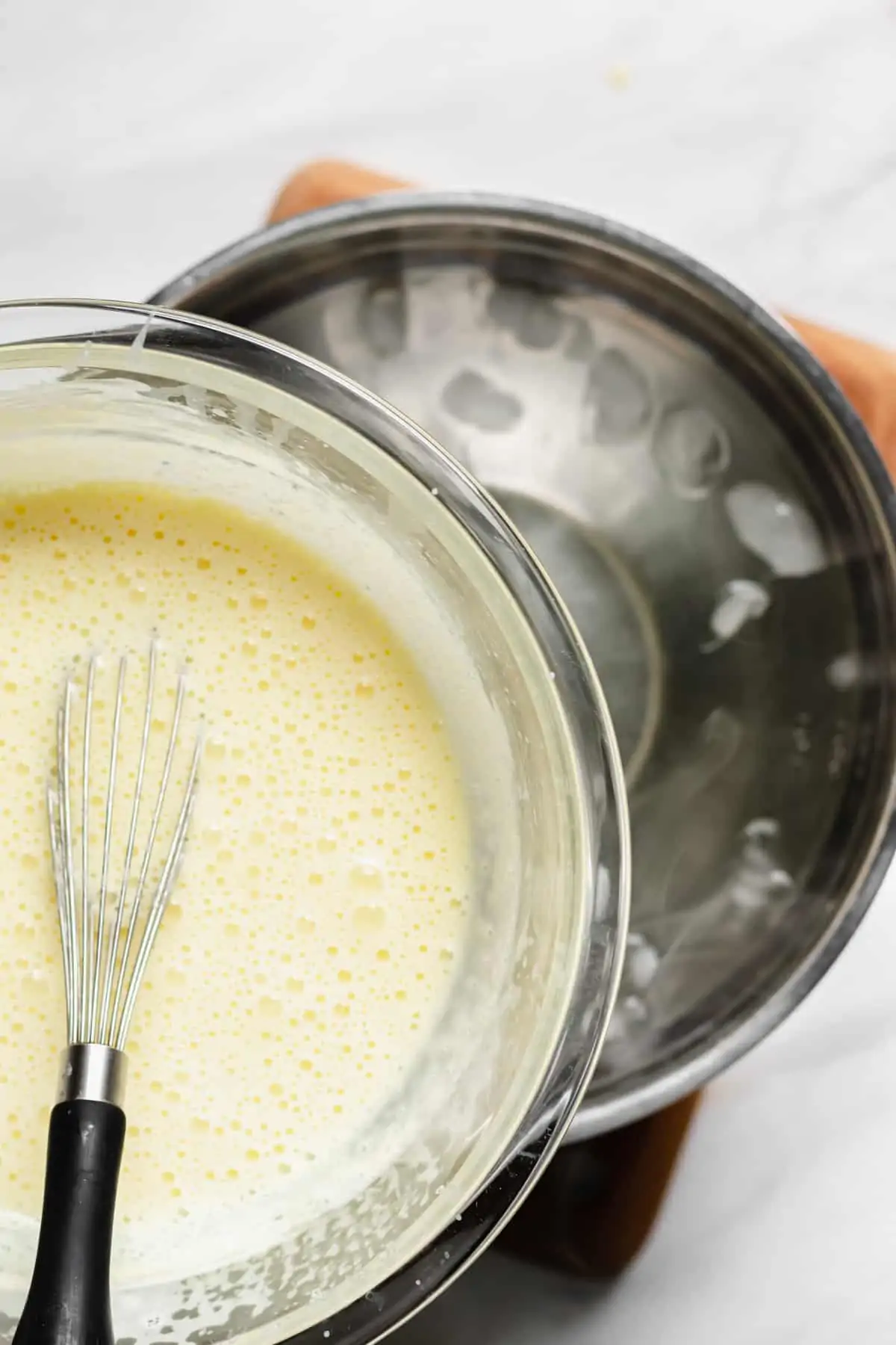 Bowl of vanilla sauce being placed onto a bowl of ice water.