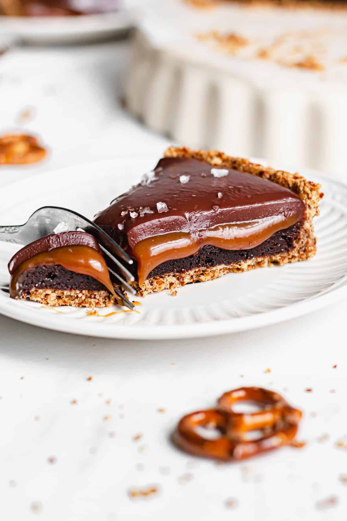Slice of chocolate caramel tart with a fork removing the tip.