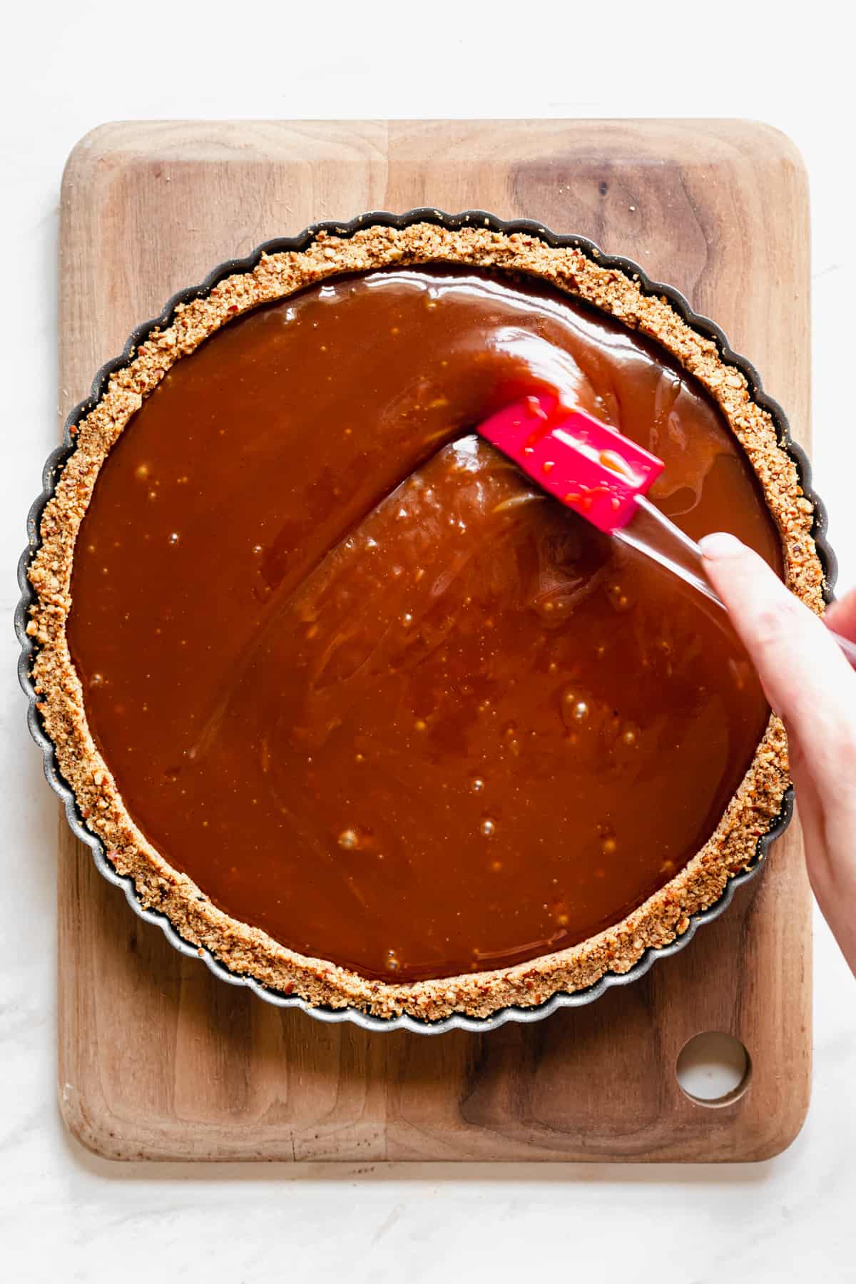 Caramel being spread to meet the edges of the pie