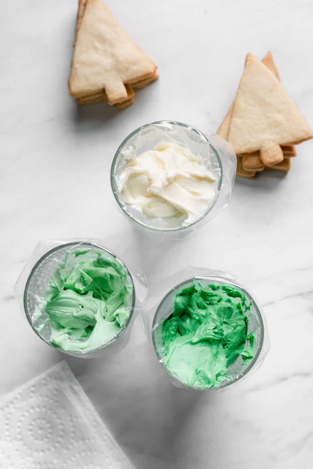 Dark green, light green, and white frosting in piping bags