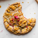 Closeup of a cornflake cereal cookie with a bite removed.