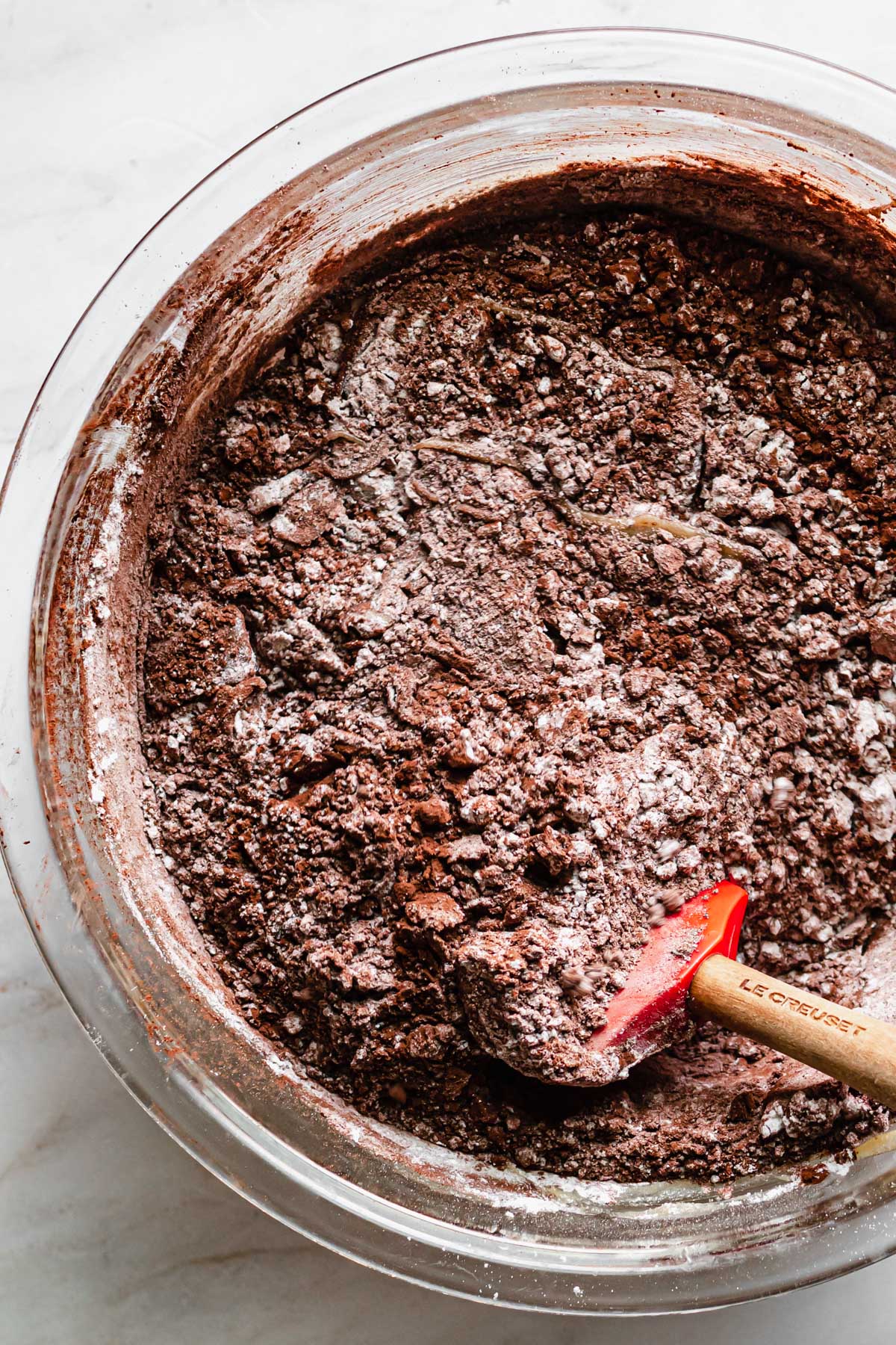 A spatula folds together the chocolate cherry brownie batter.