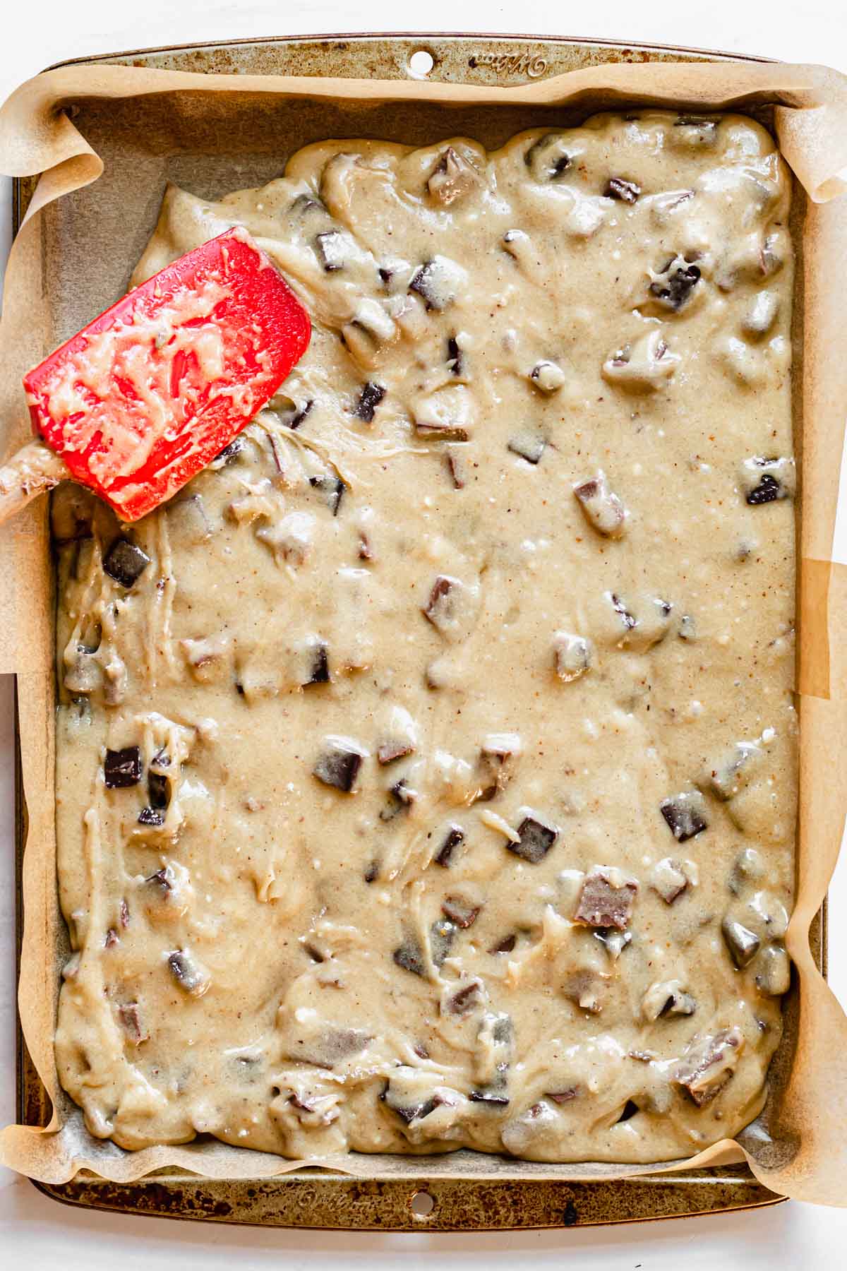 Blondie batter being spread into a quarter sheet pan.