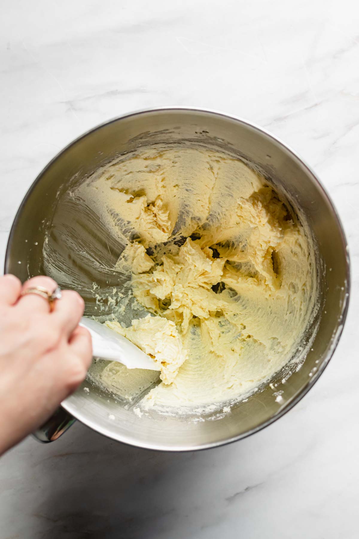 Overhead shot of creamed butter and sugar with a spatula scraping down the sides.