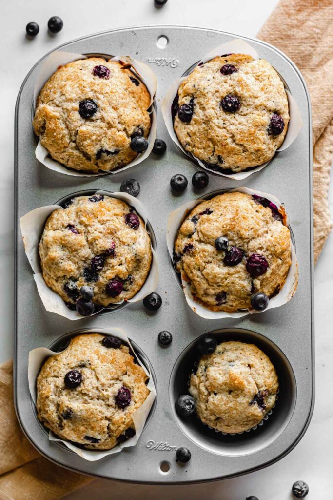 Five baked jumbo muffins and one regular sized muffin in a muffin tin.