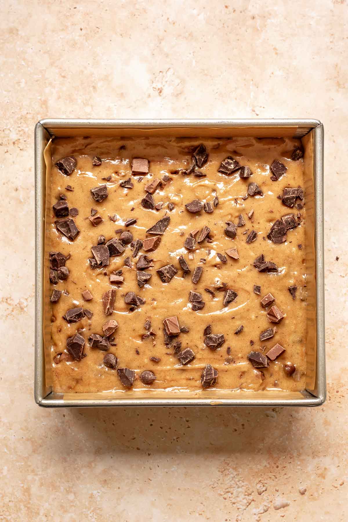 Chocolate is scattered on top of blondies before baking.