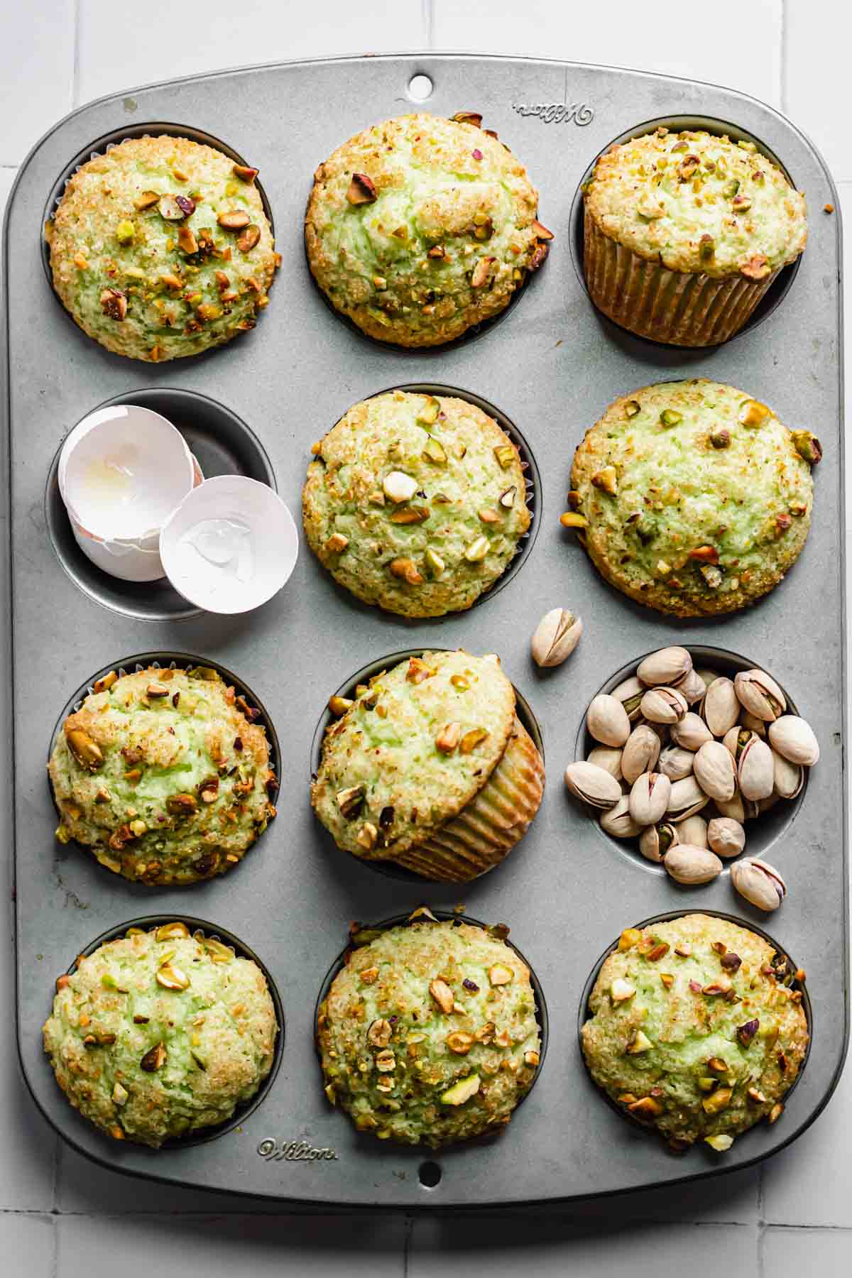 Finished muffins in a pan with egg shells an pistachios filling two of the wells.
