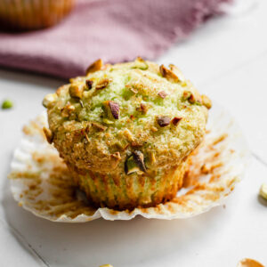 One pistachio muffin with the liner pulled down.