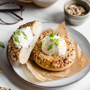 Two bialy bagels on a plate. Once is sliced down the center.