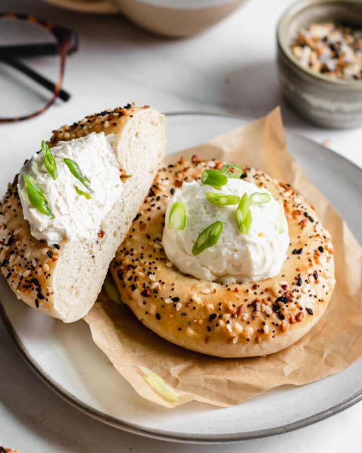 Two bialy bagels on a plate. Once is sliced down the center.