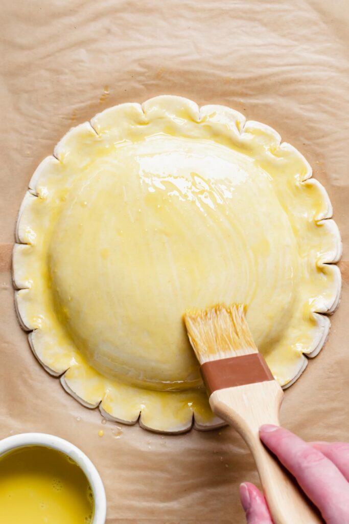 A pastry brush adds on the second round of egg wash.