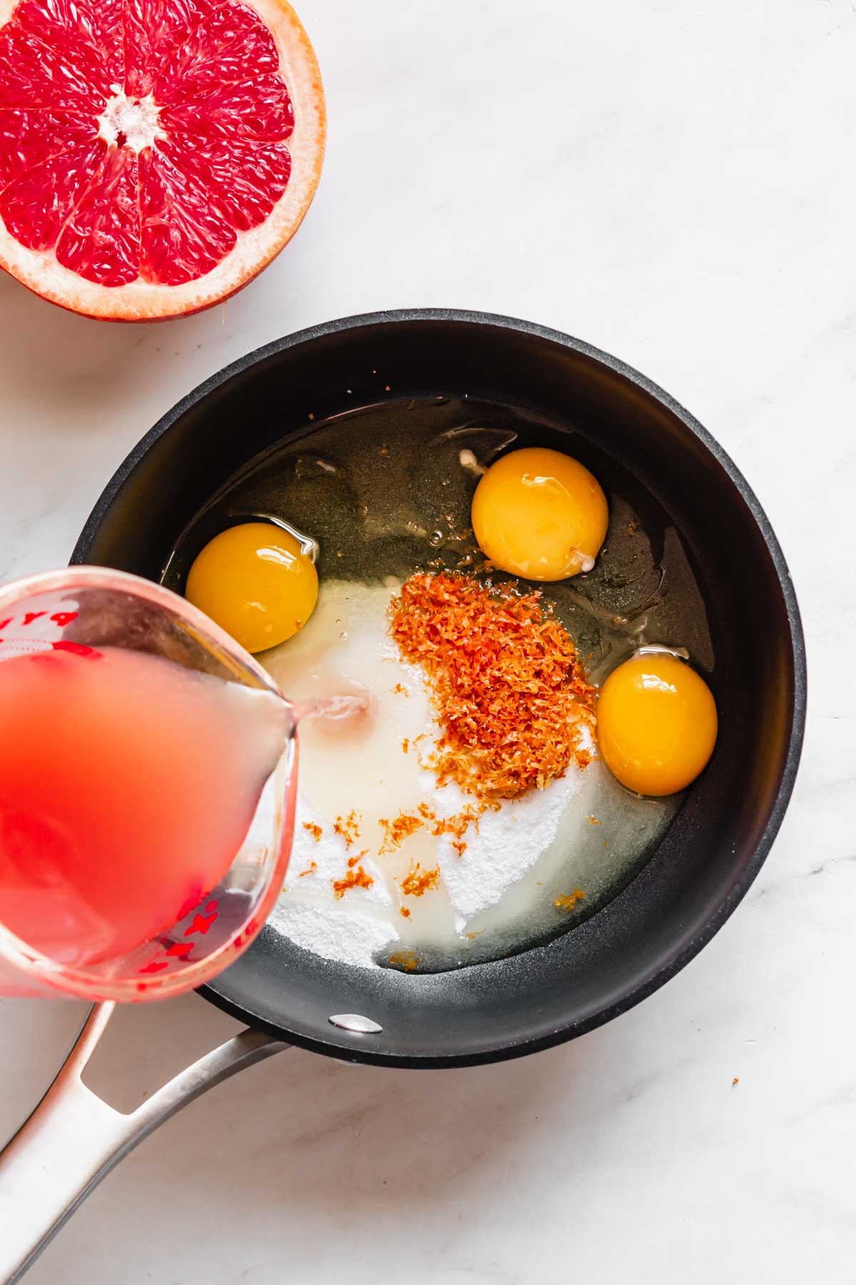 Grapefruit juice poured into a saucepan with the curd ingredients.