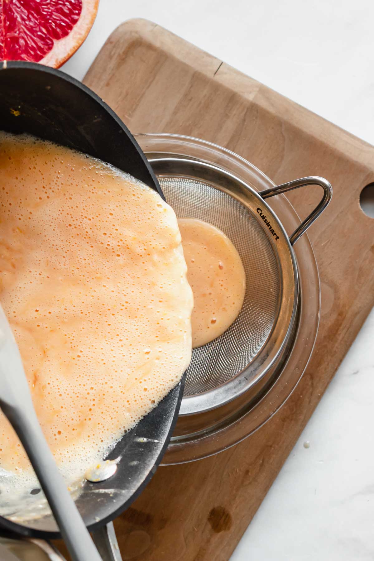 The curd gets poured through a fine mesh sieve into a bowl.