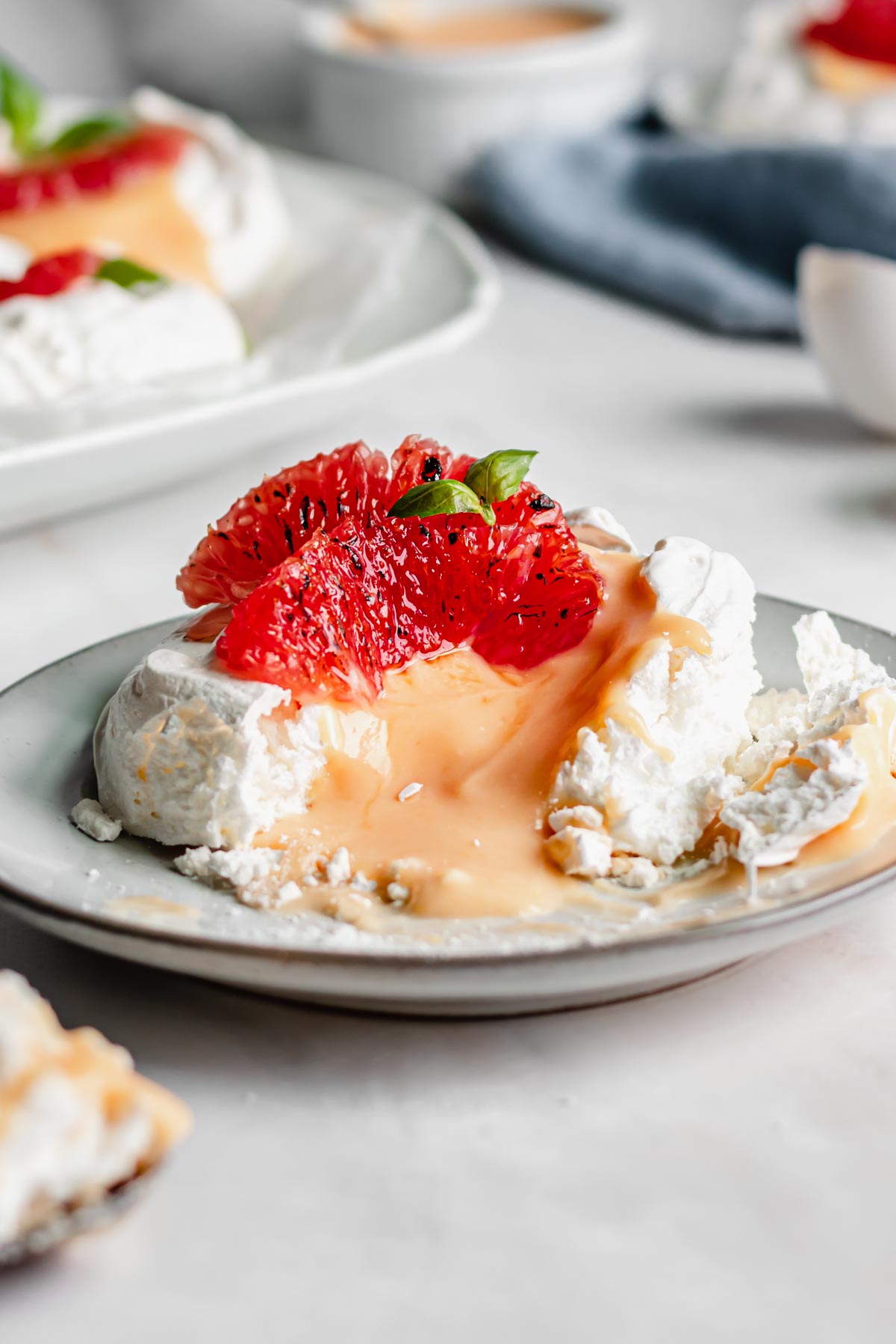 A single pavlova on a plate with a bite removed and the curd running out.