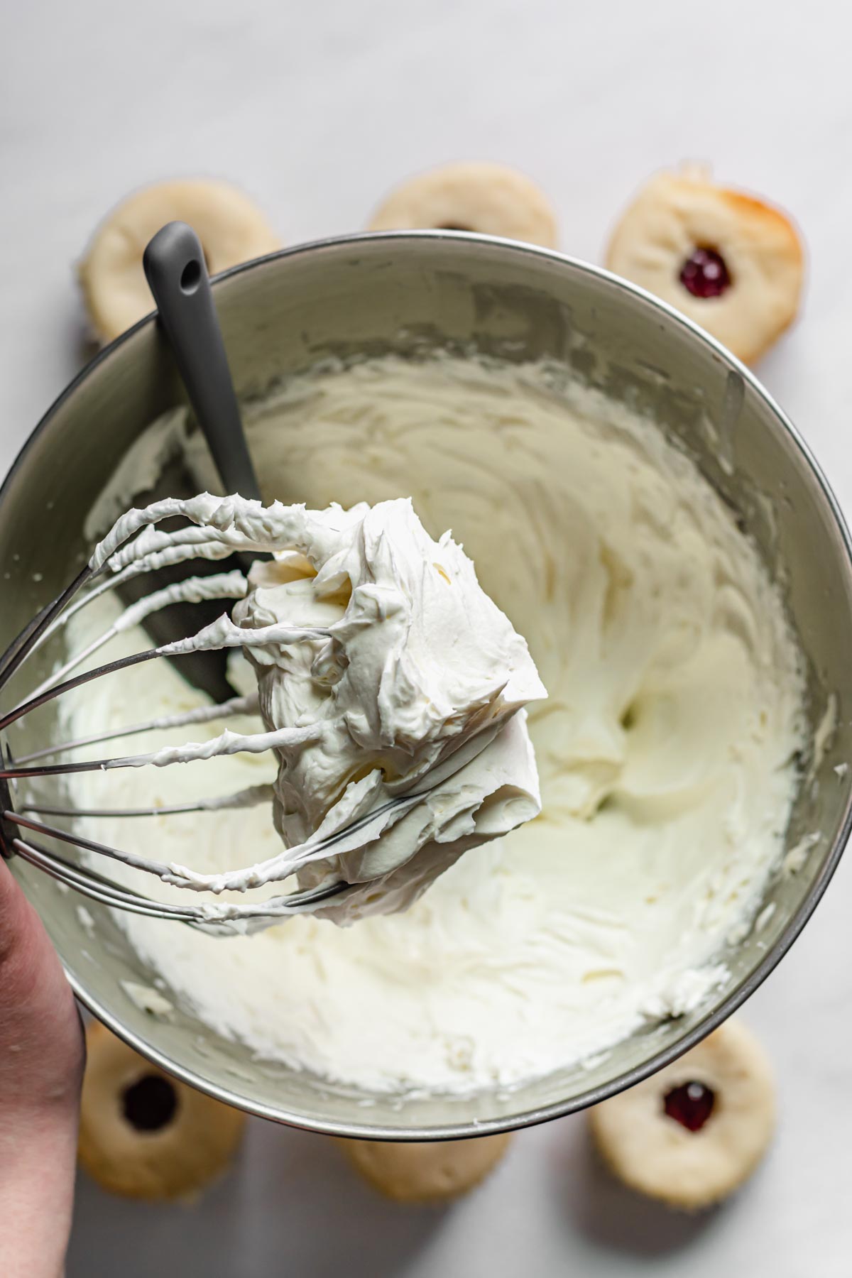Whipped cream cheese frosting on the tip of a whisk attachment.
