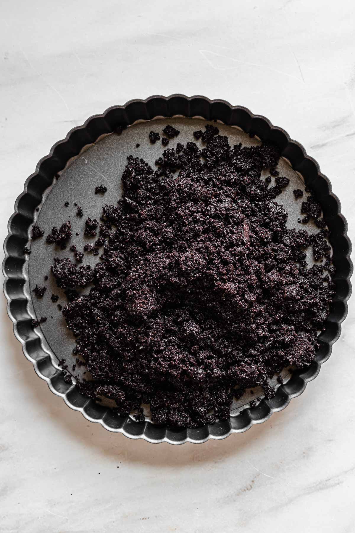 Oreo crumbs in a tart pan.