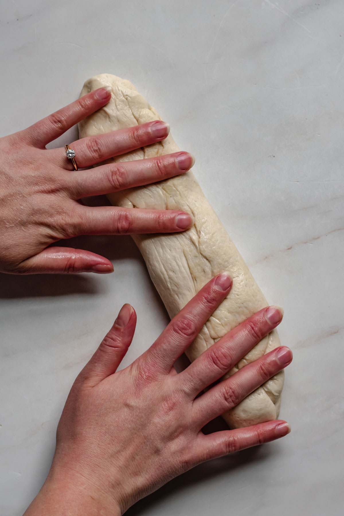 Two hands roll out a piece of pretzel dough.