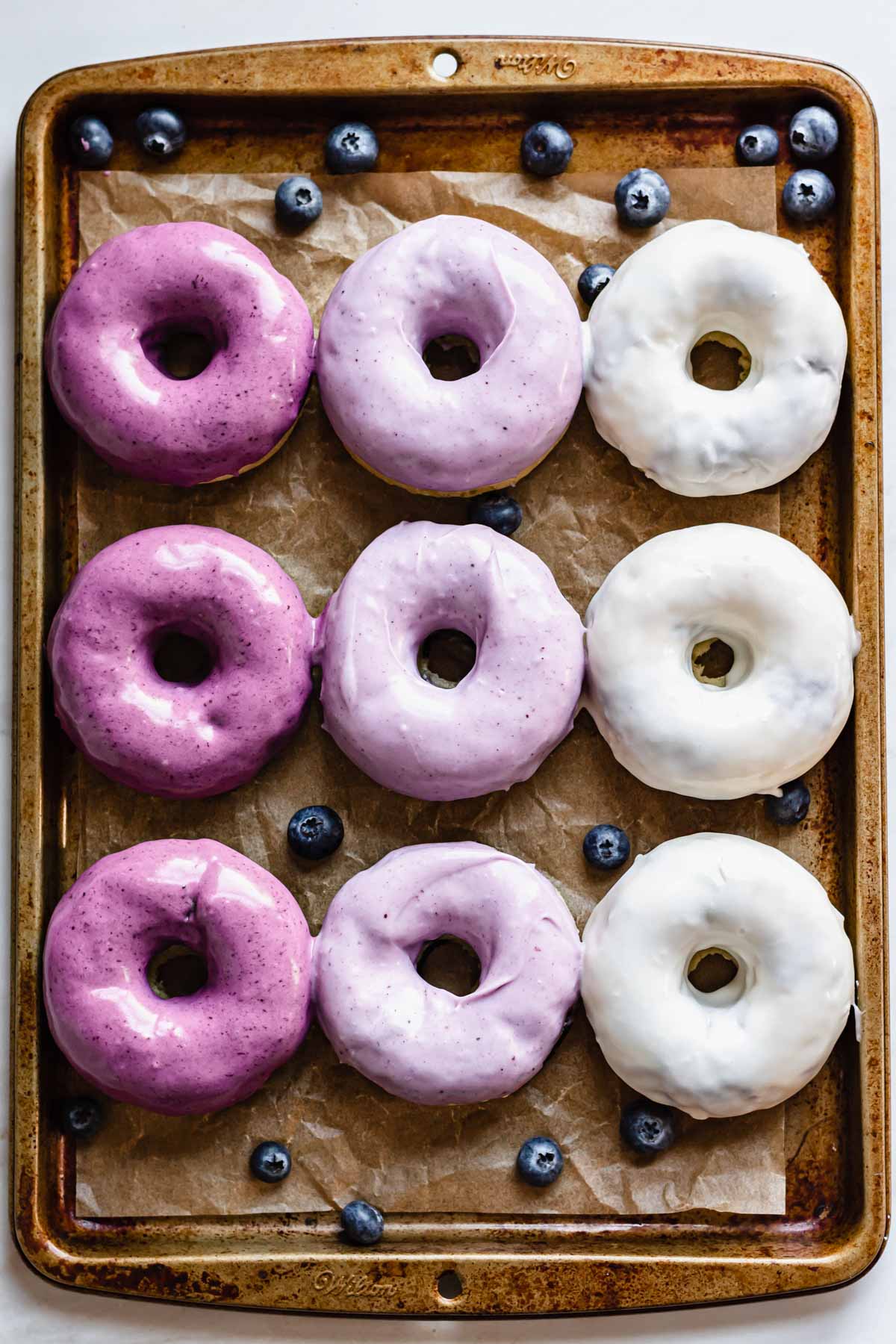 Pan of ombre blueberry glazed donuts.