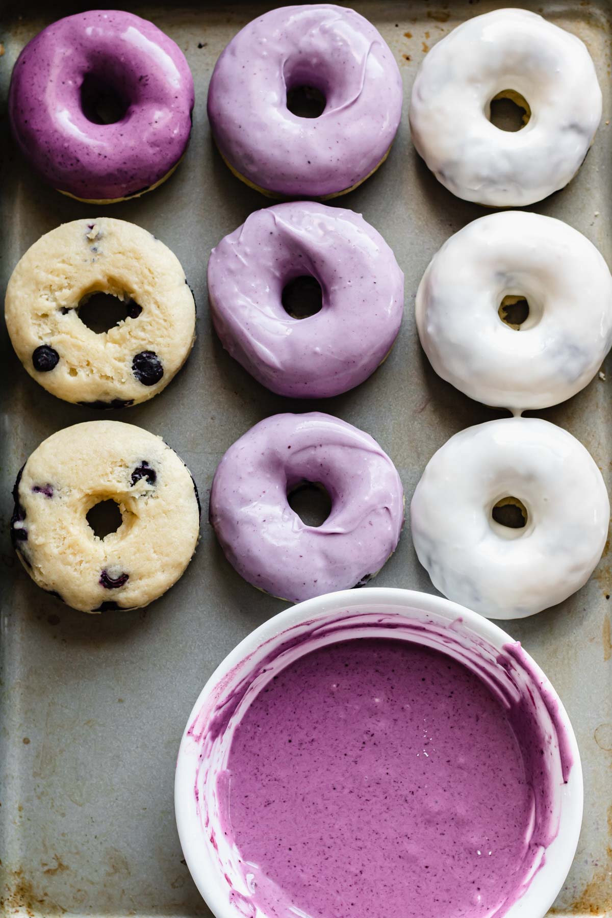 Donuts on a pan with blueberry glaze.