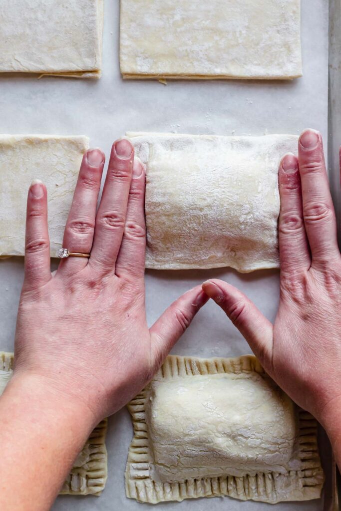 Fingers pushing down the dough to seal.