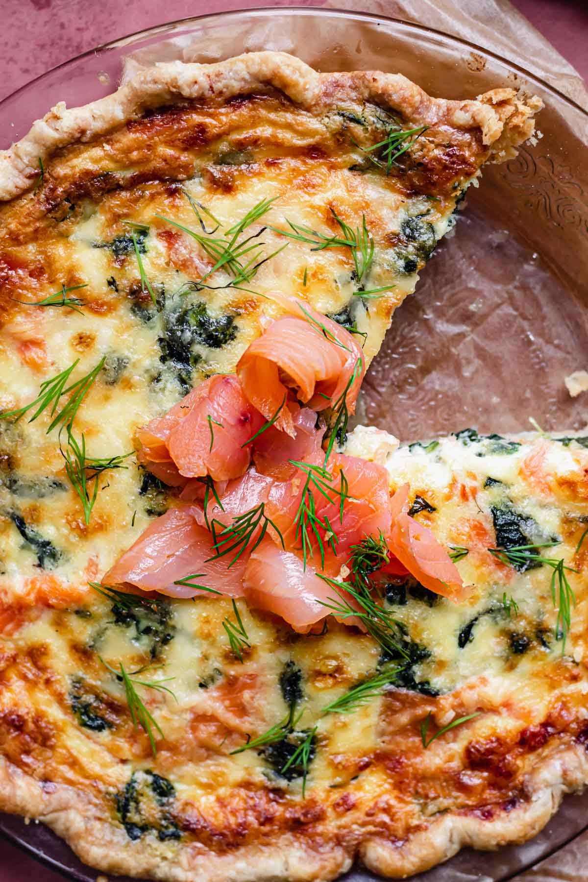 Smoked salmon and spinach quiche with a slice removed.