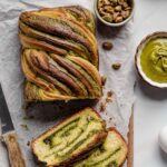 Pistachio babka loaf with two slices next to it.