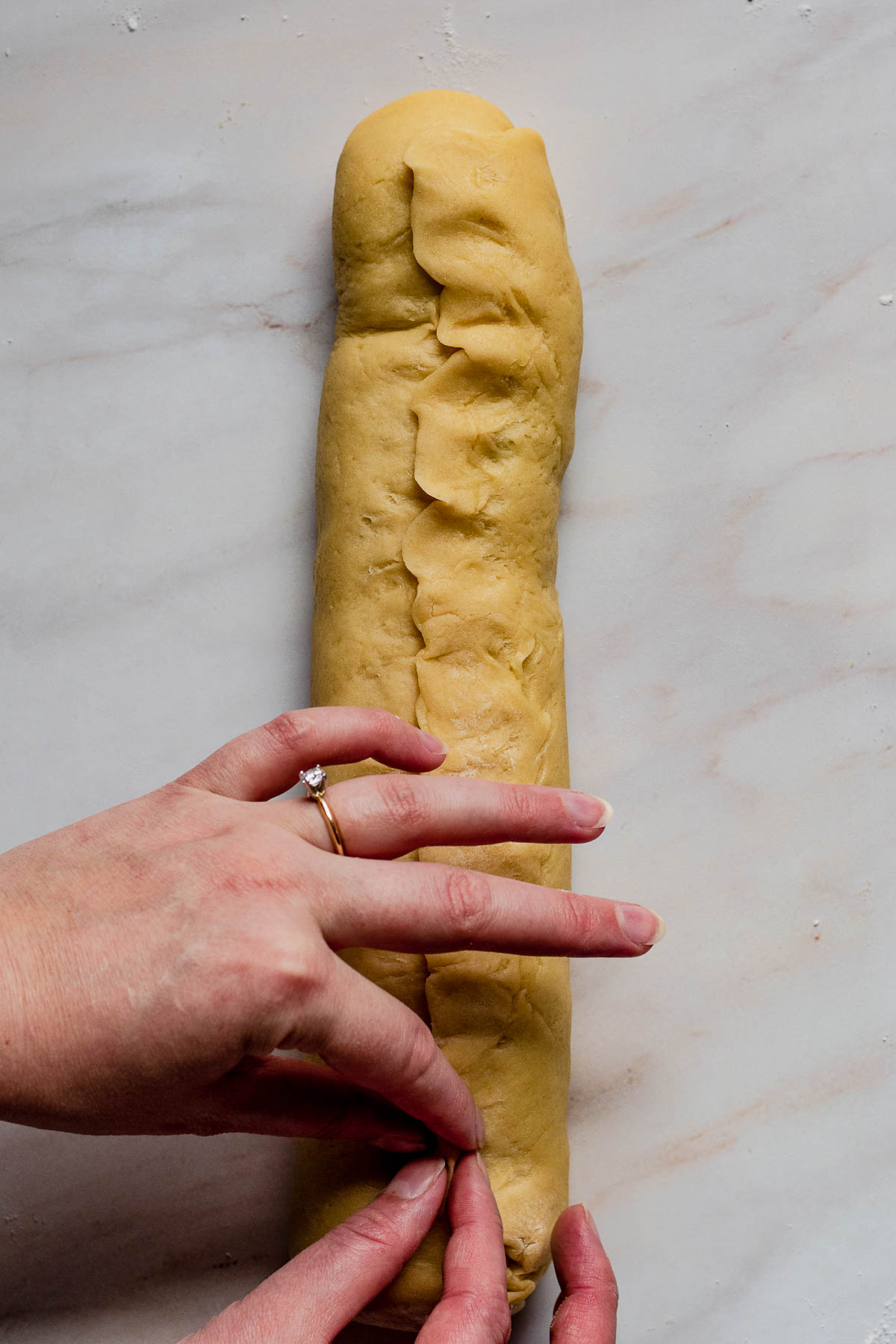 Hand pinching the dough closed.