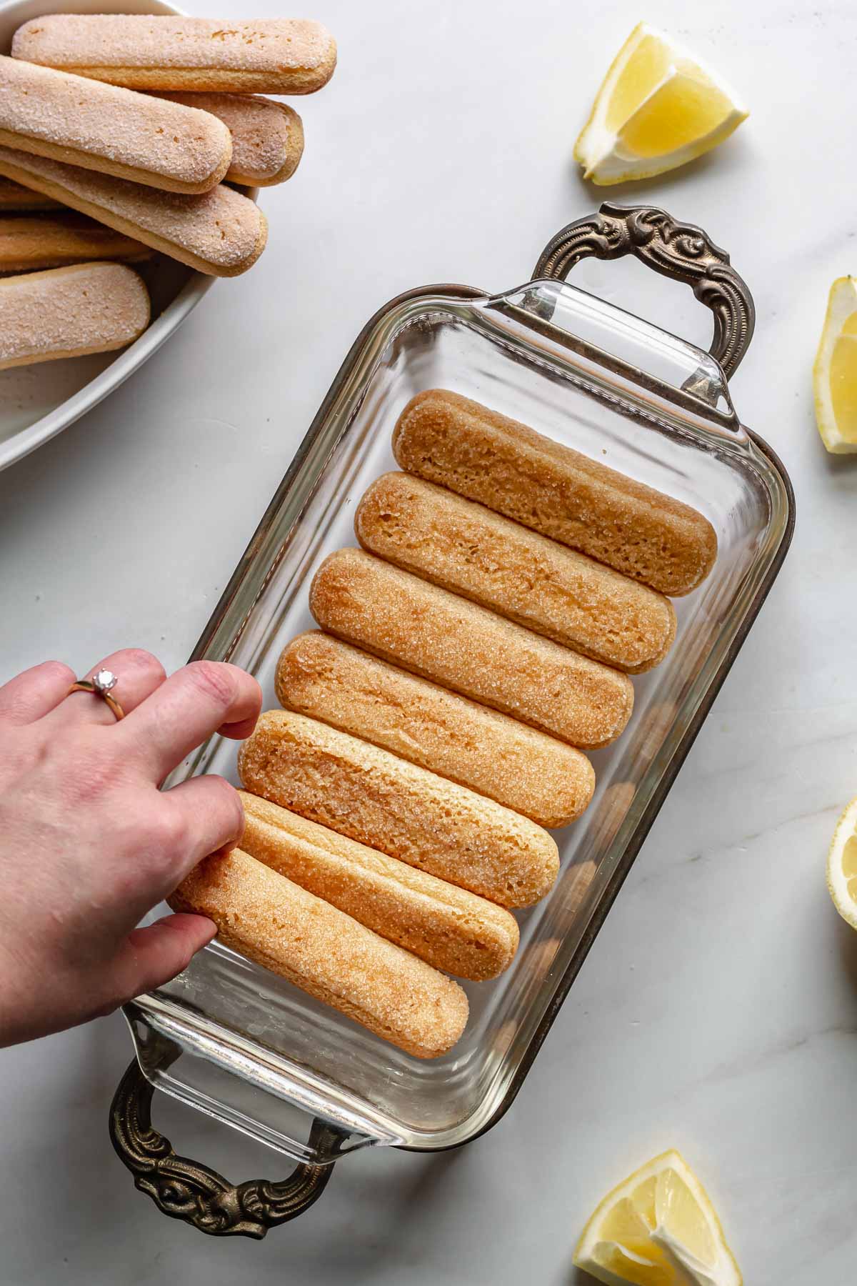 Layering lady fingers in the bottom of the loaf pan.