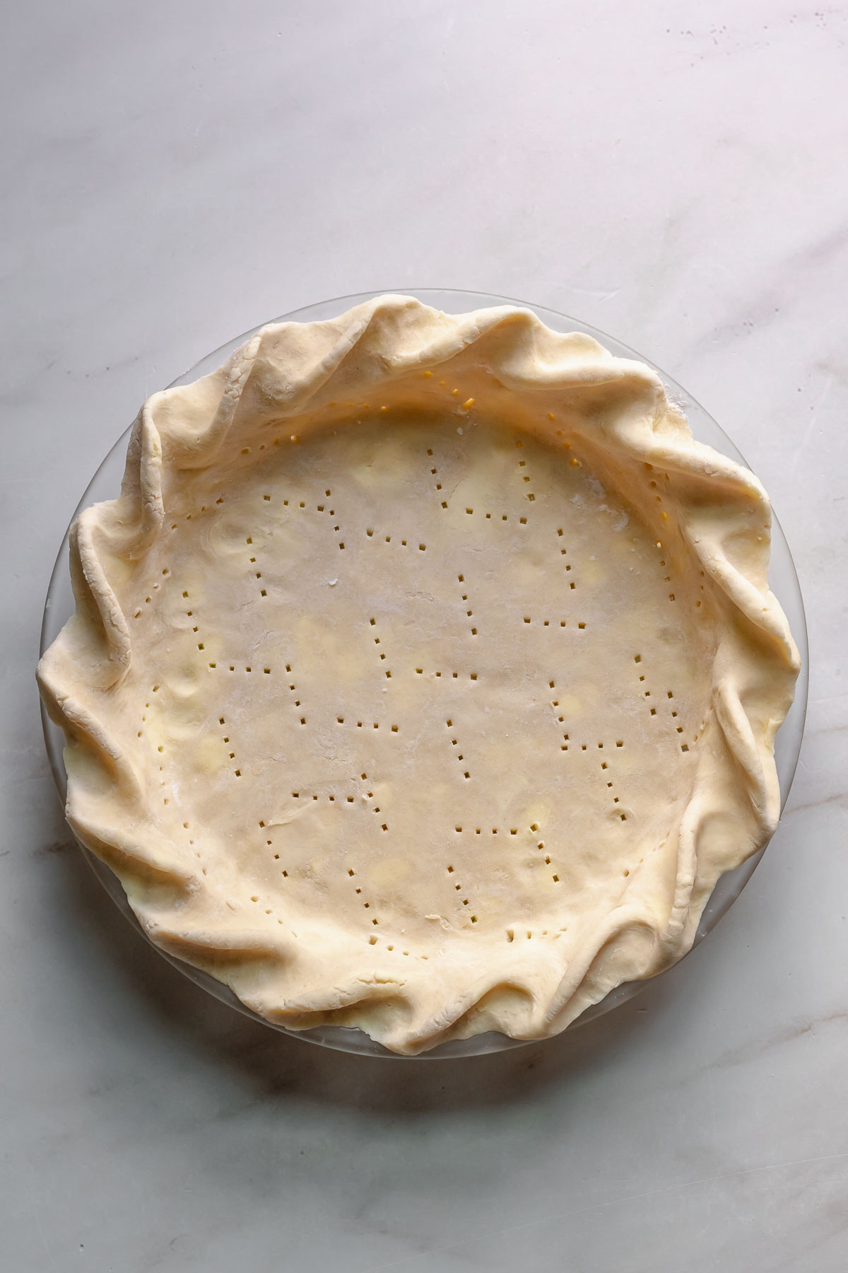 Pie crust fitted to a pie pan and crimped and docked.