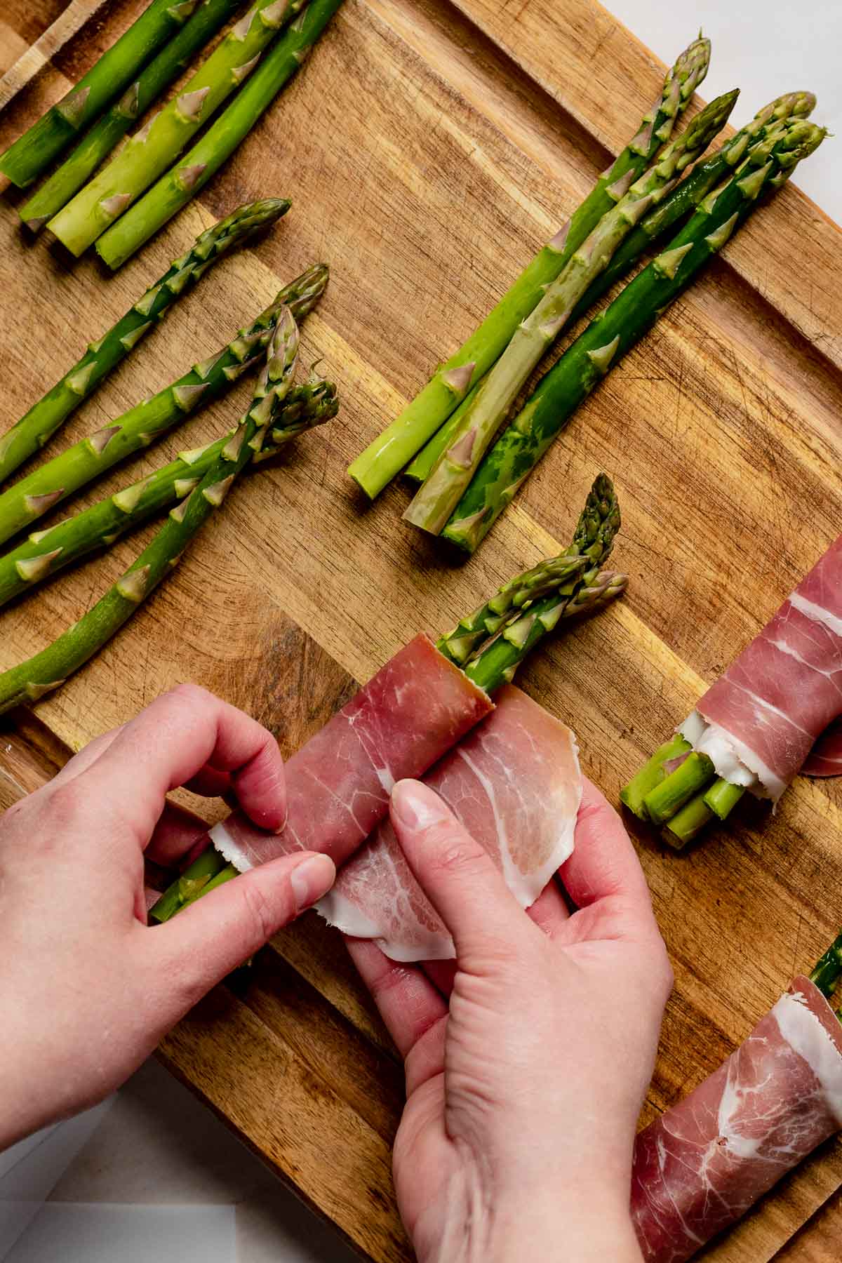 Wrapping prosciutto around asparagus bundles.