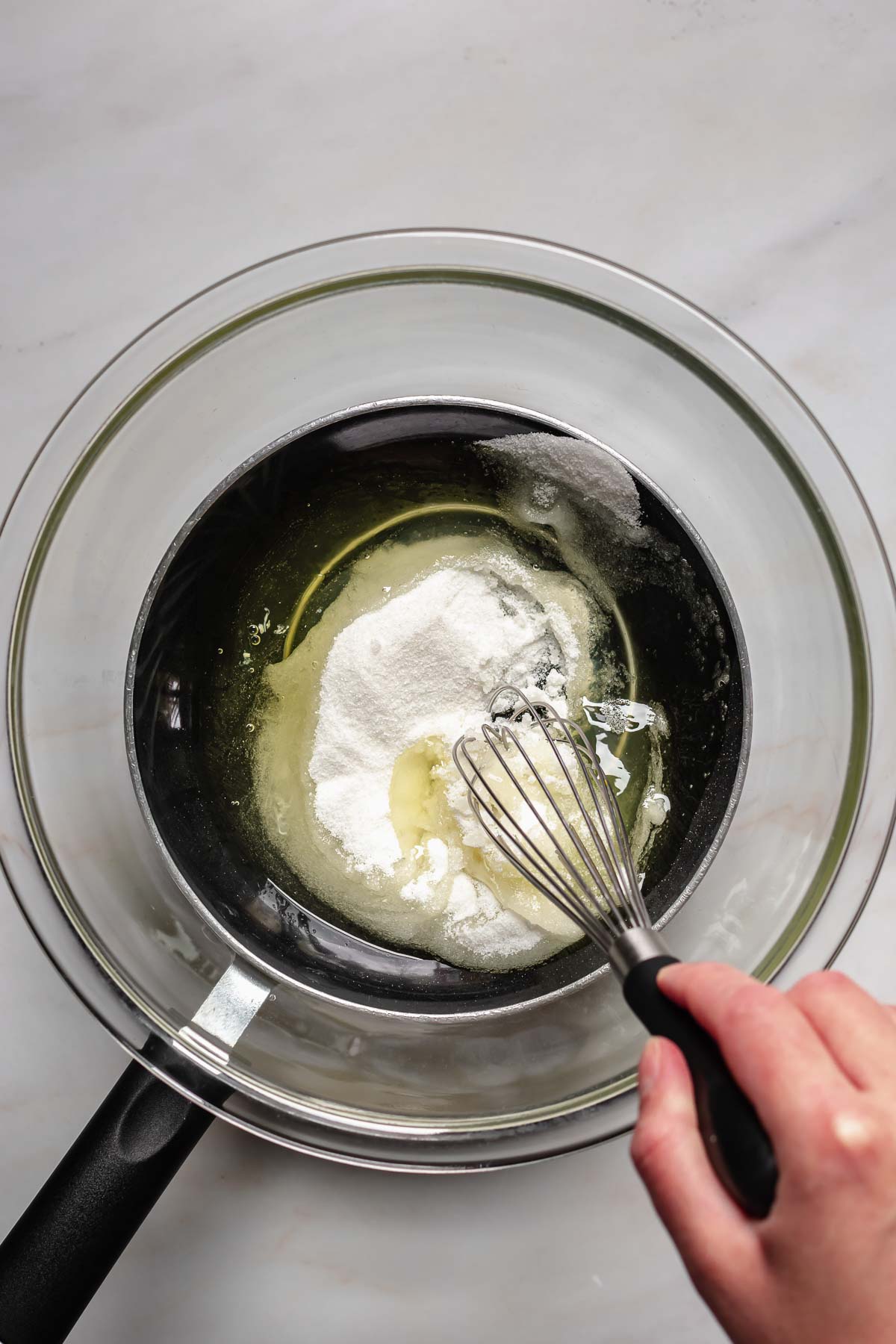 Hand whisks egg whites and sugar in a bowl.