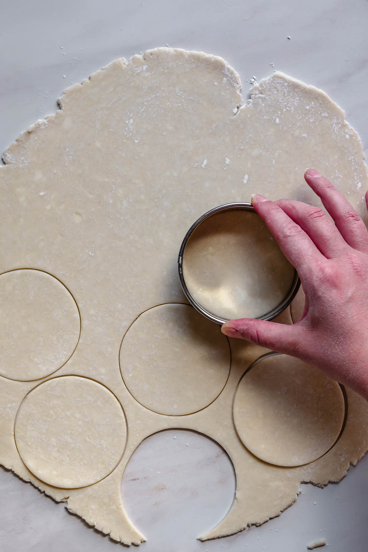 Cutting dough rounds with a cookie cutter.
