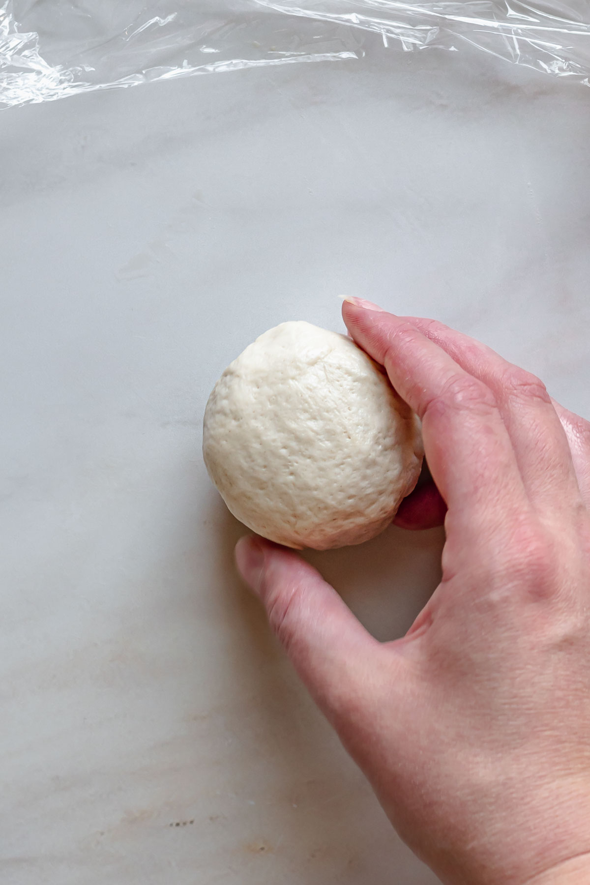 A hand rolls a ball of filled pretzel dough.