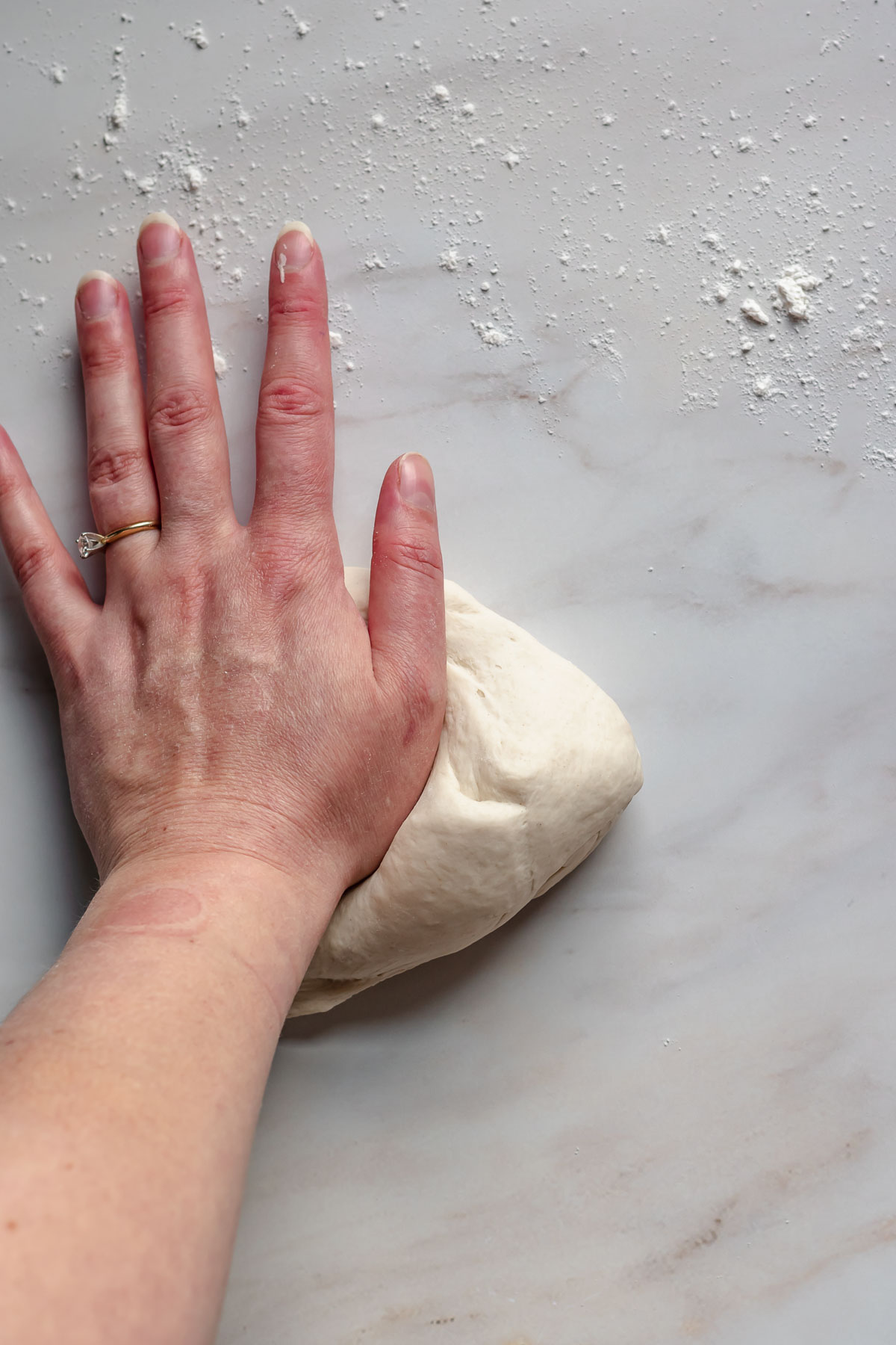 A hand kneading pretzel dough.