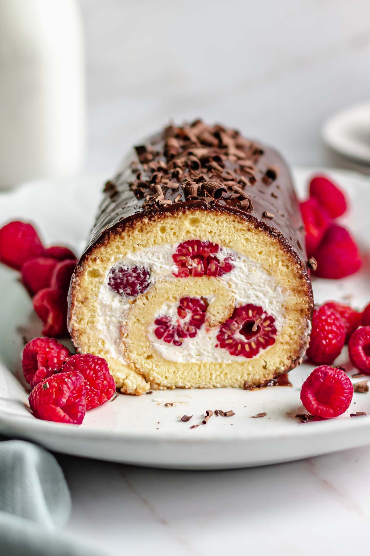 Vanilla Swiss roll with a slice removed to show raspberries inside.