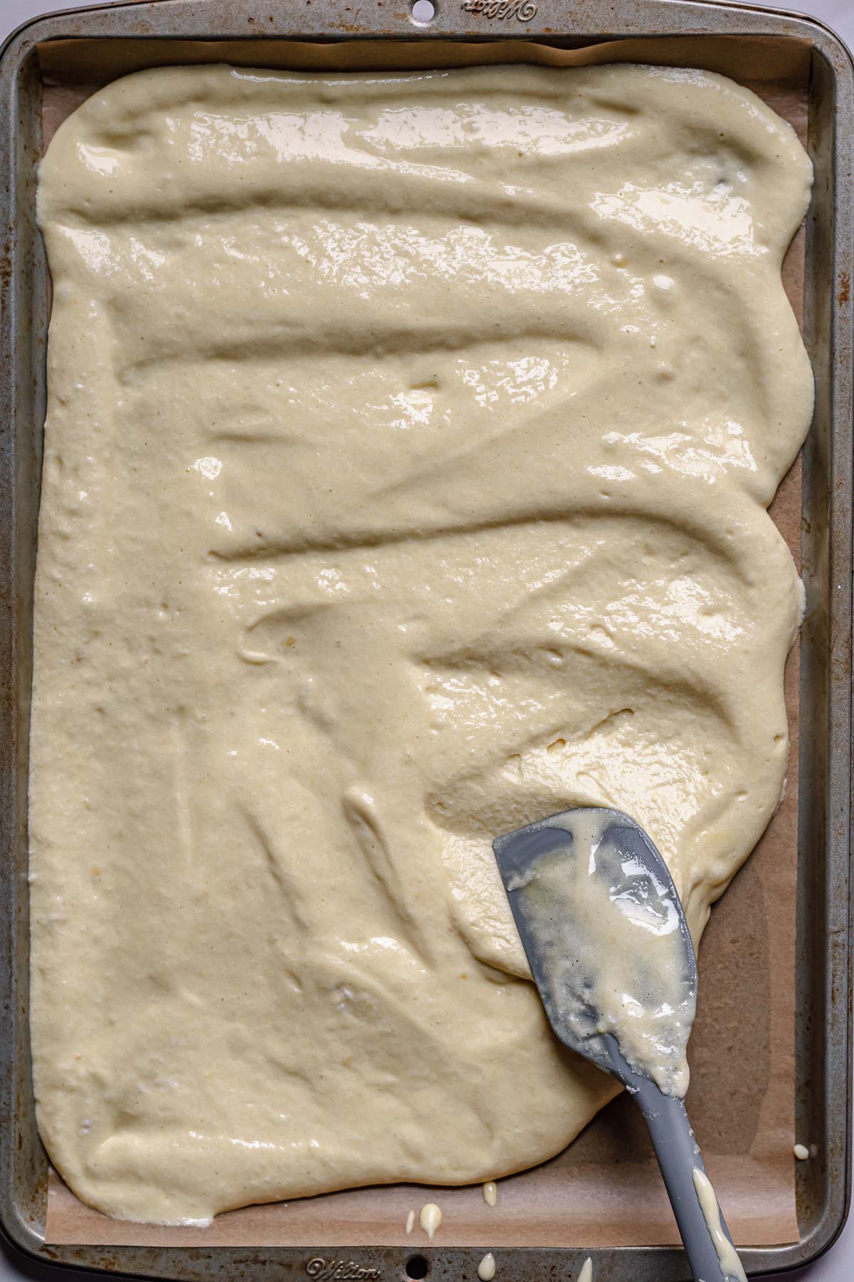 A spatula spreads batter evenly in the pan.