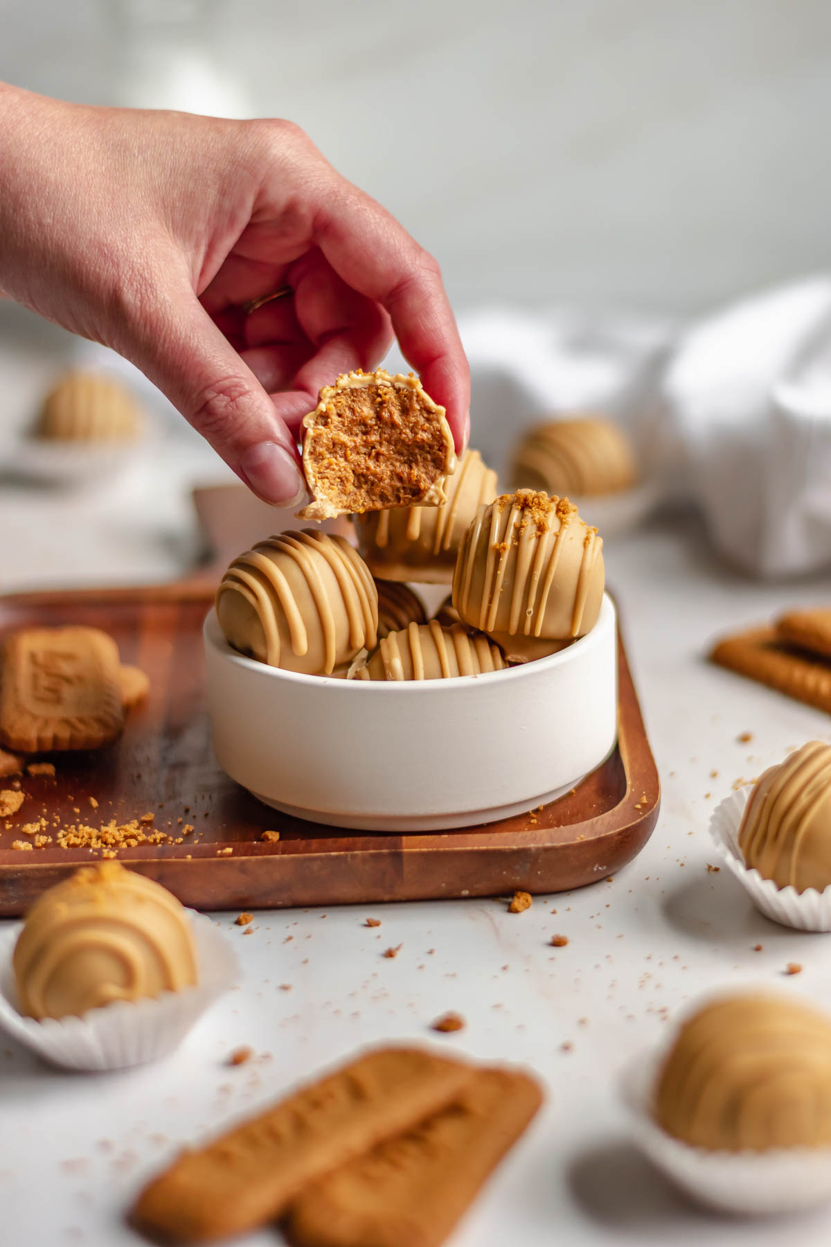A hand reaching in to remove a biscoff truffle from a bowl.