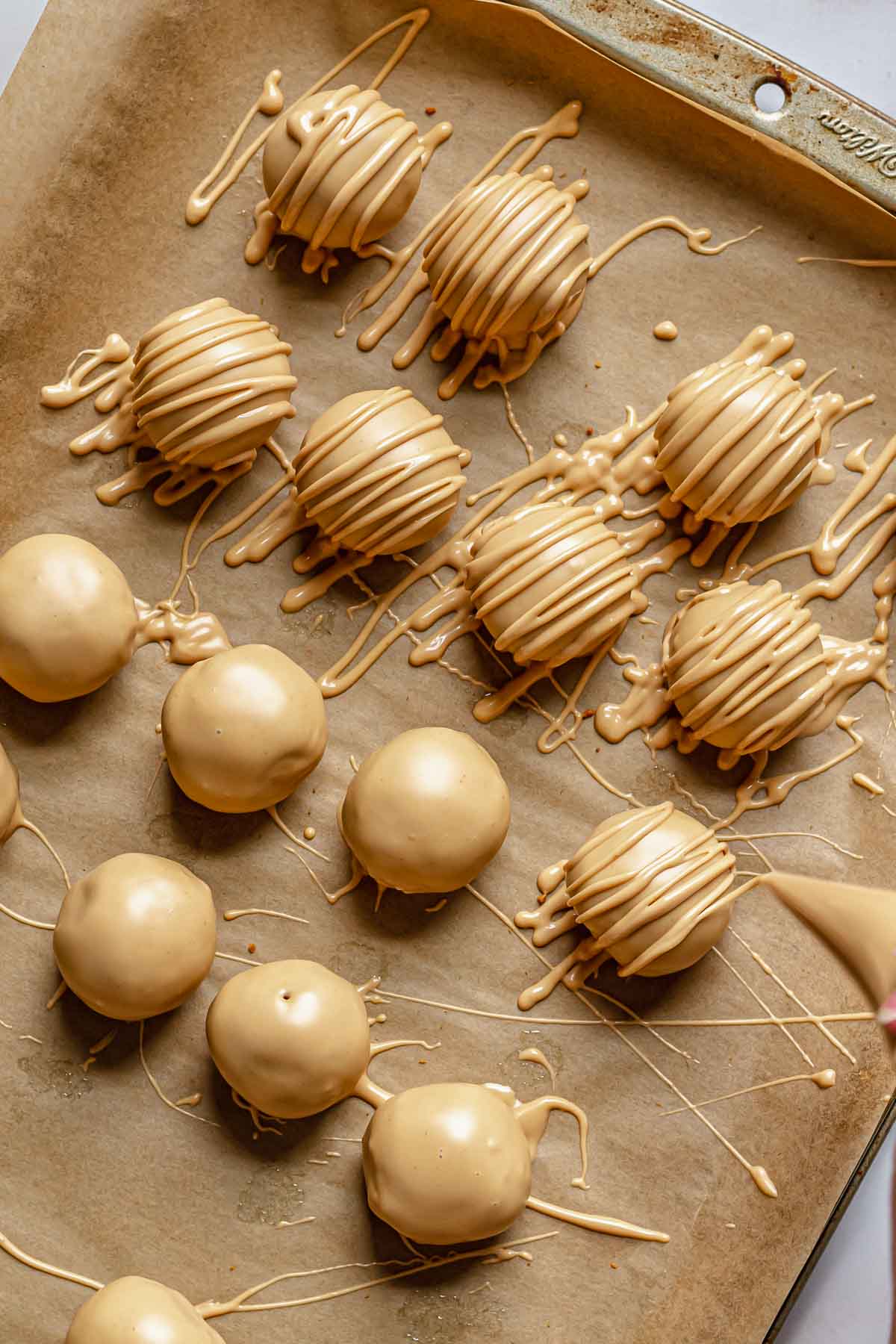 A piping bag making drizzles on top of the truffles.