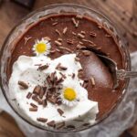 Dark chocolate pots de creme with whipped cream and a spoon in it.