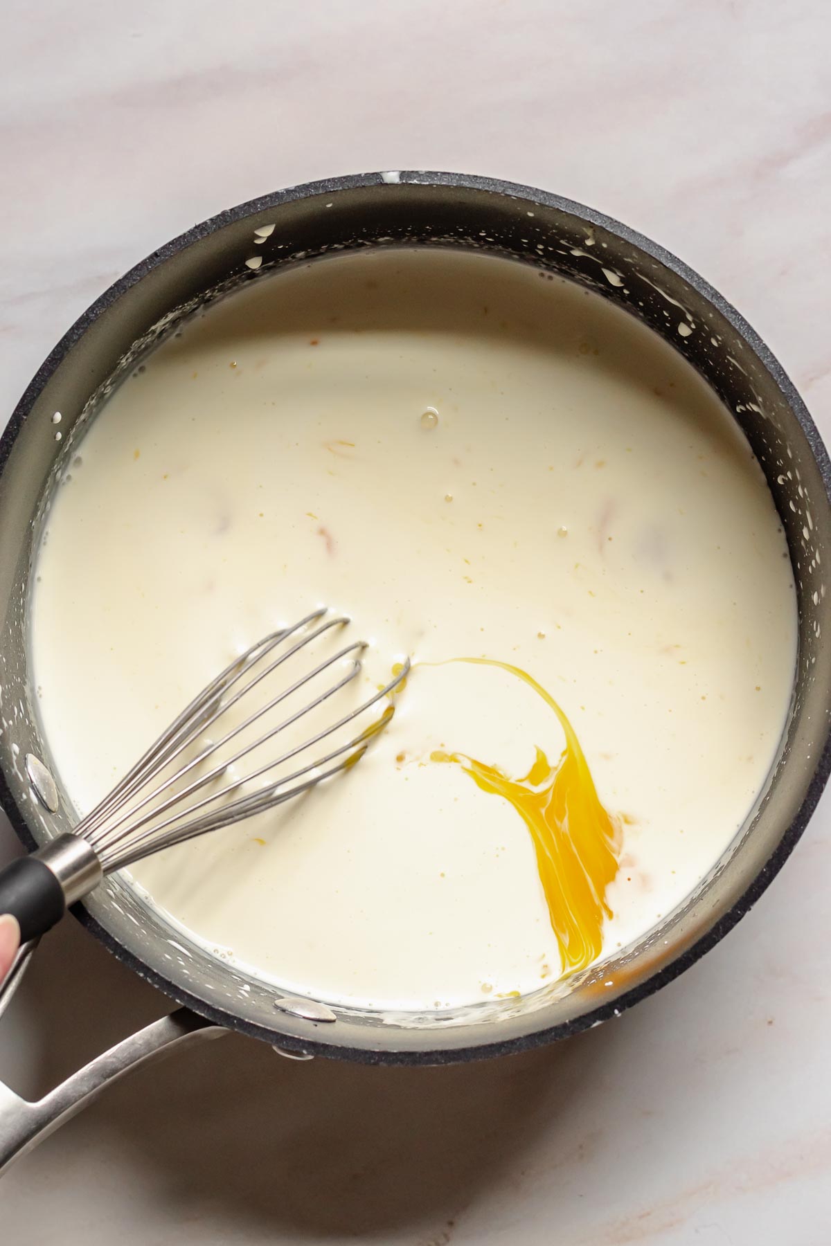 Whisking egg yolks and cream in a pot.