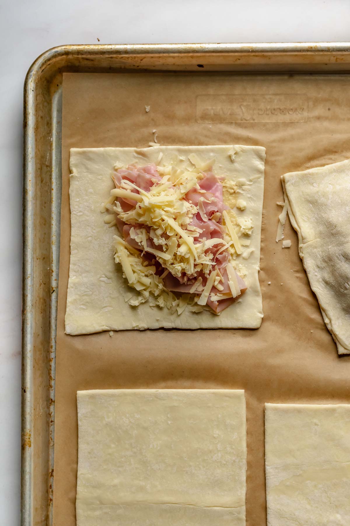 Cheese and ham on a puff pastry square.