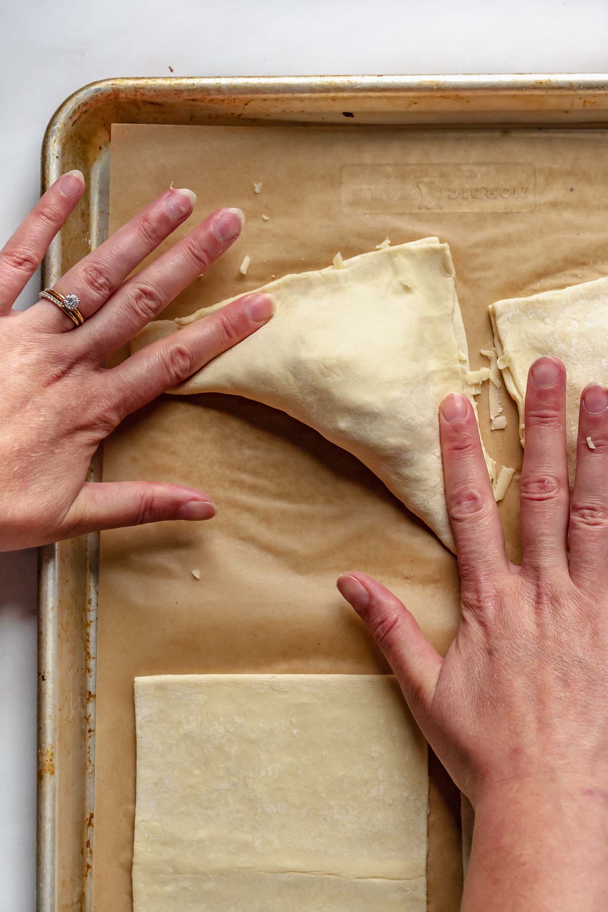 Fingers press the turnovers to seal it closed.