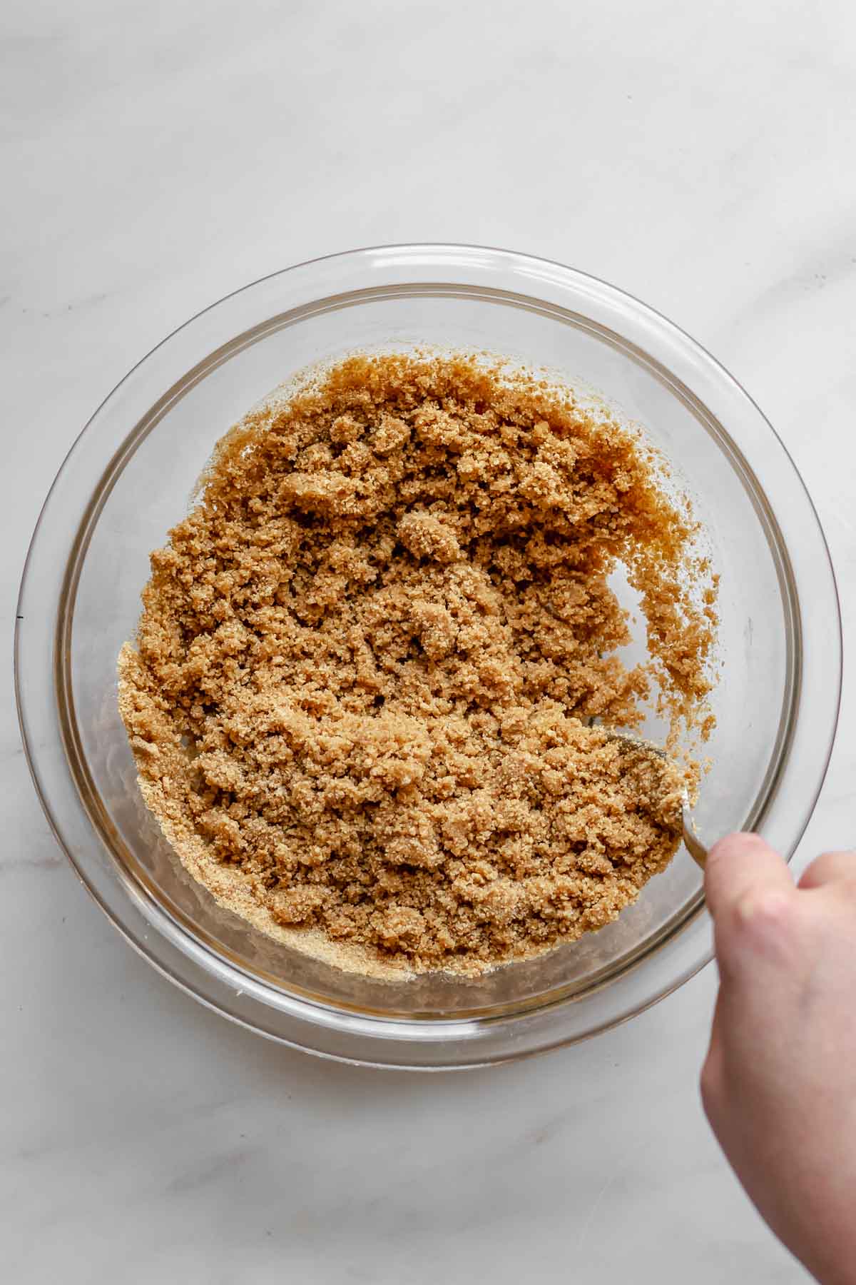 Graham cracker crumbs being stirred in a bowl.