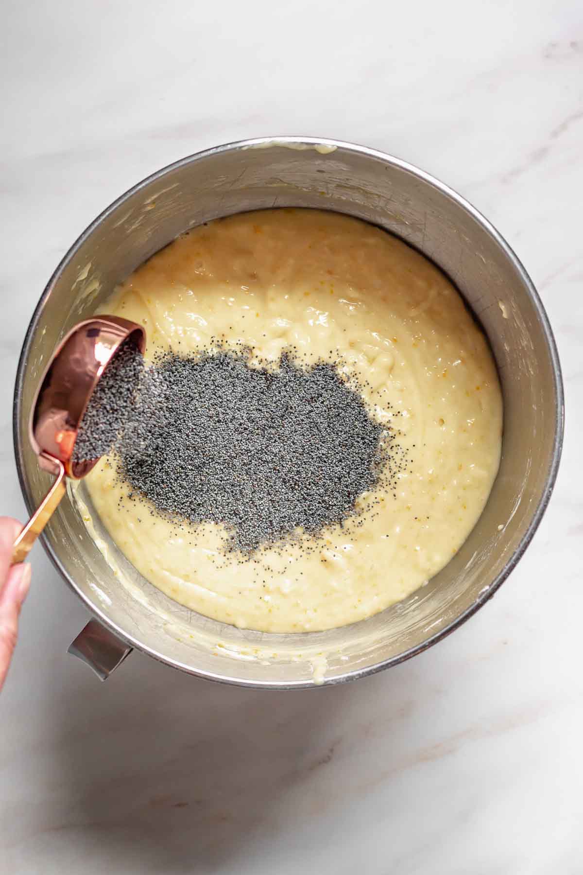 Poppy seeds pouring into cake batter.