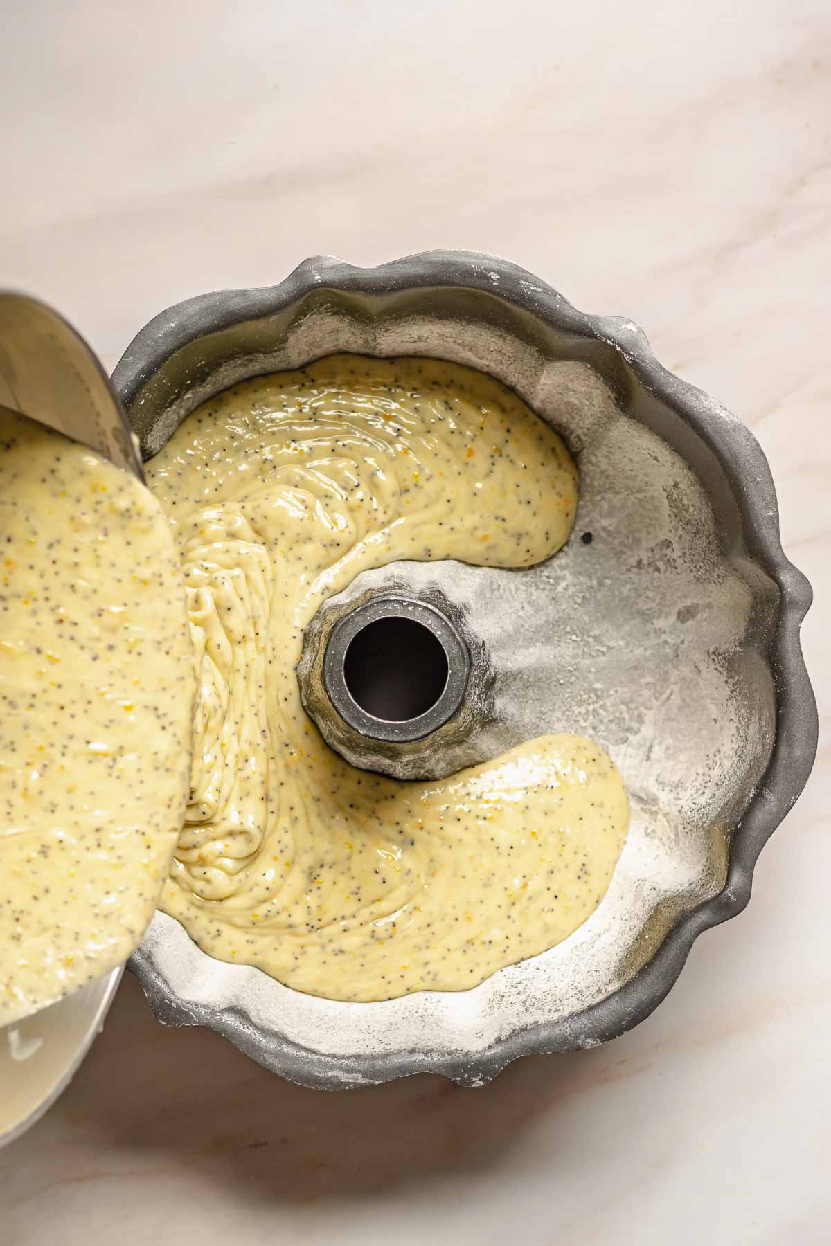 Cake batter pouring into a prepared bundt pan.