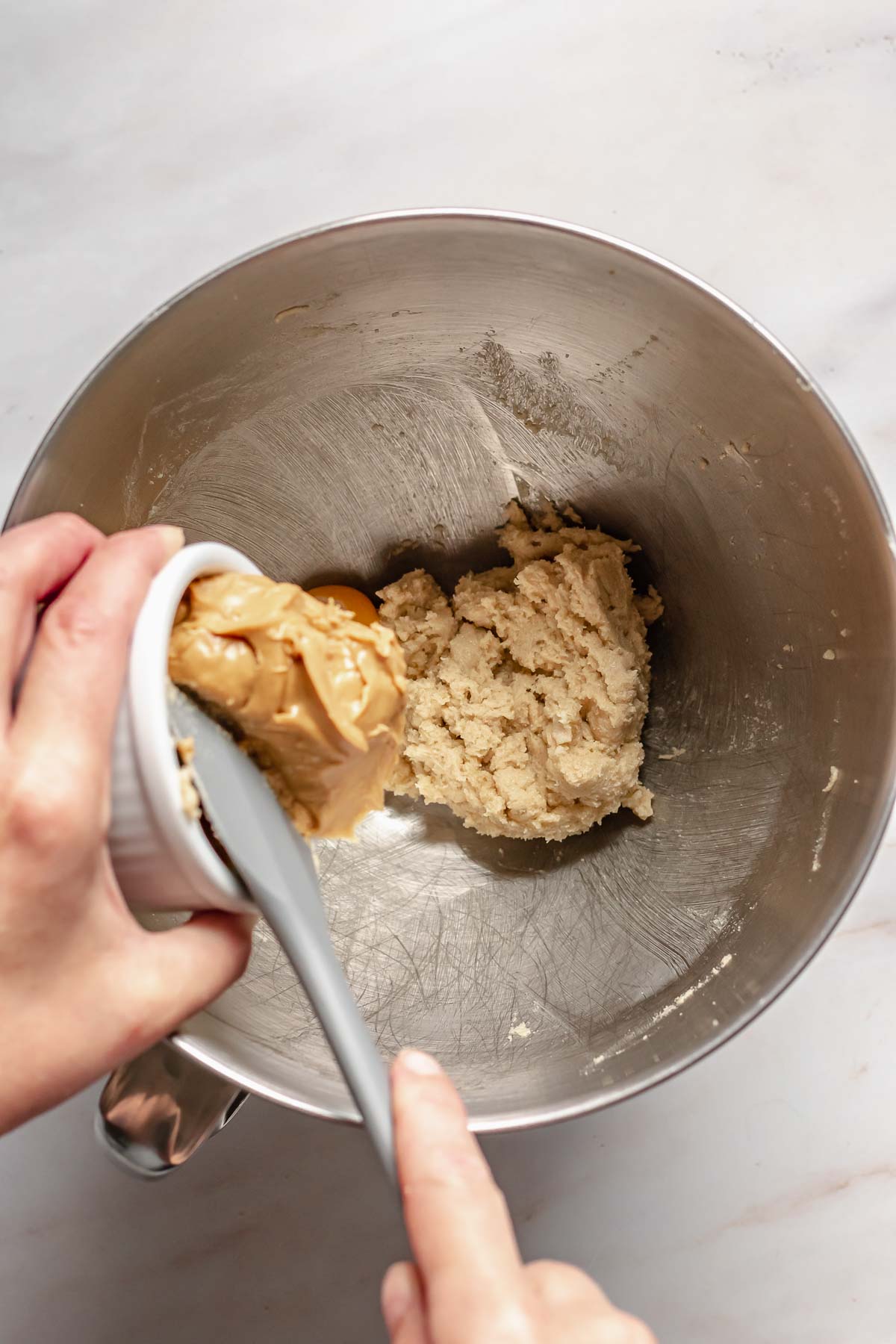 Pouring peanut butter into the creamed ingredients.